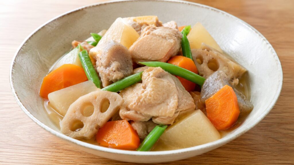 鶏肉、大根、にんじん、レンコン、こんにゃく、インゲンが彩りよく盛り付けられた和食「根菜と鶏肉の煮物(筑前煮)」の写真。『お隣の天使様』第3話で、真昼が周にタッパーに入れてお裾分けした絶品手料理を彷彿とさせる一枚。
